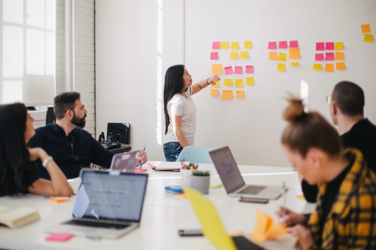 Classroom photo with students studying around a table with post it notes